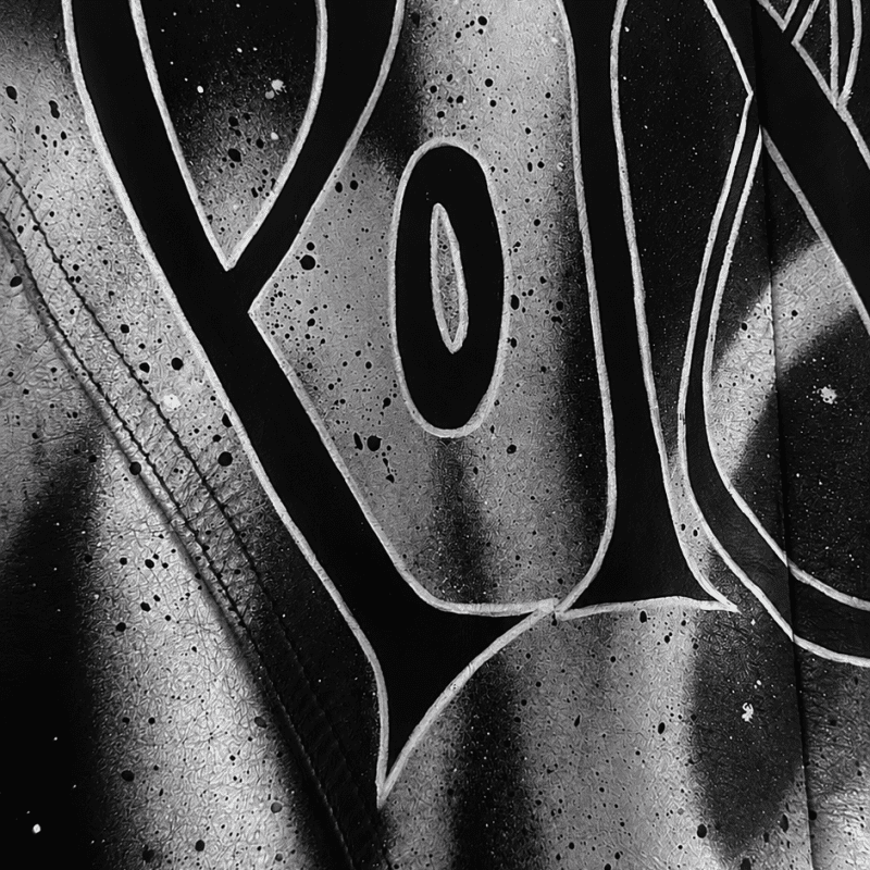 Front view of a hand-painted vintage Bison black leather jacket featuring the word "Poison" in custom calligraphy with abstract white brushstroke artwork.